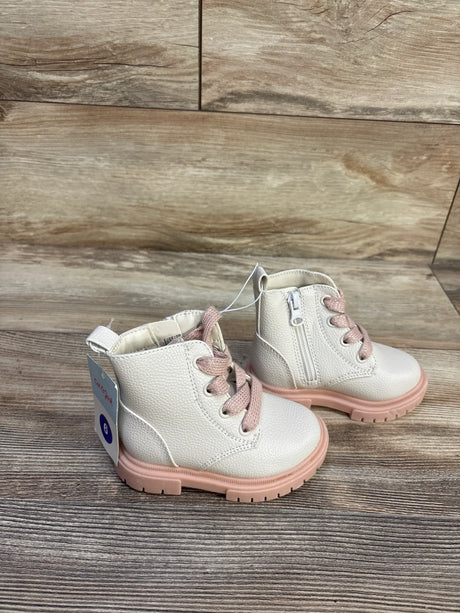 Front-side view of Cat & Jack Amaya toddler combat boots in cream with pink laces and pink lug sole showing side zipper on wood background