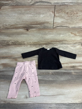 Children's outfit with black long-sleeve ribbed shirt and pink polka dot leggings on wooden floor