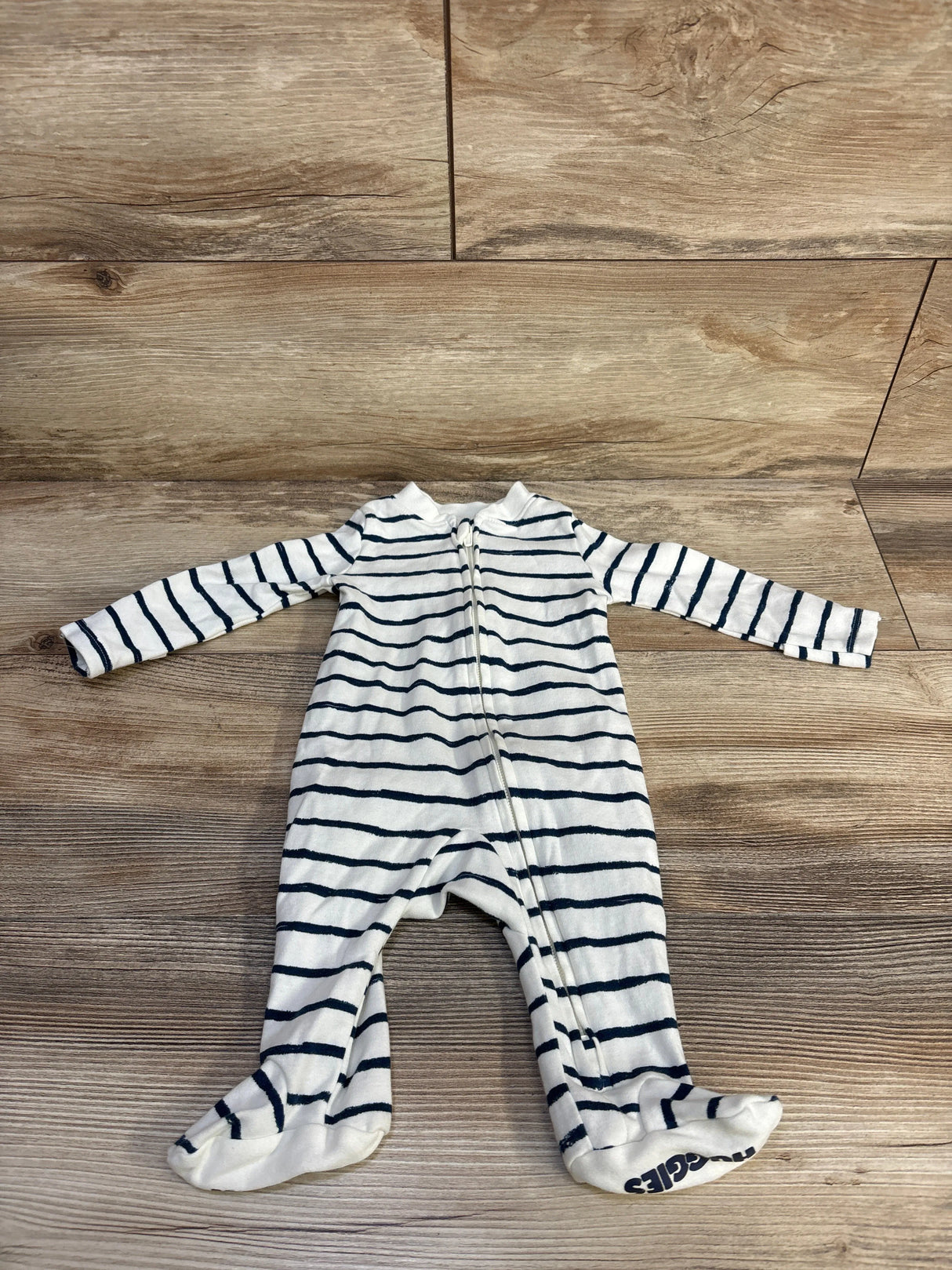 Front view of Huggies white footed striped sleeper (3 months) showcasing navy horizontal stripes and a front zipper on wood floor background