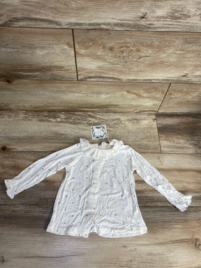 white children’s long sleeve shirt with gold polka dots and ruffled collar on wooden floor