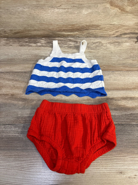 Top-down view of baby 4th of July two-piece: blue-and-white striped tank and red cotton bloomers on wood background
