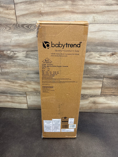 Front view of Baby Trend Nursery Center Playard Tanzania packaging showing product labeling on a wood floor