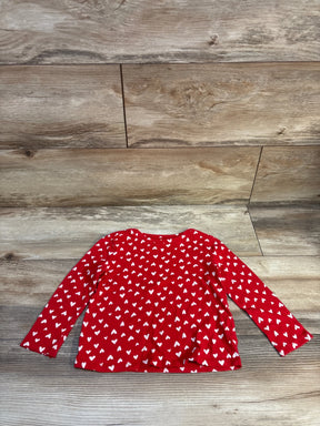 Red long sleeve toddler shirt with white heart pattern on wooden background