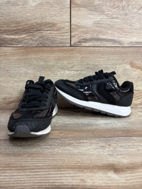 Pair of black sneakers with white soles placed on wood-textured surface and background