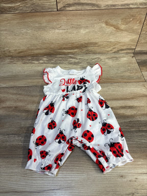 White baby romper with red ladybug print and ruffle sleeves, laid on wood floor