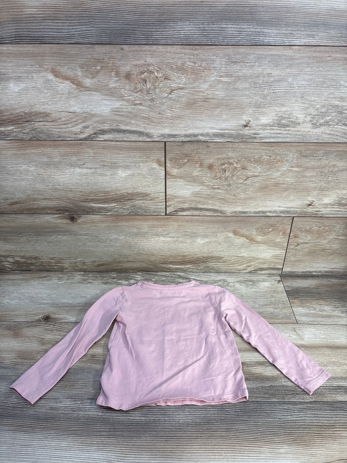 Back flat-lay of H&M light pink long-sleeve toddler shirt showcasing crew neckline and long sleeves on wood floor