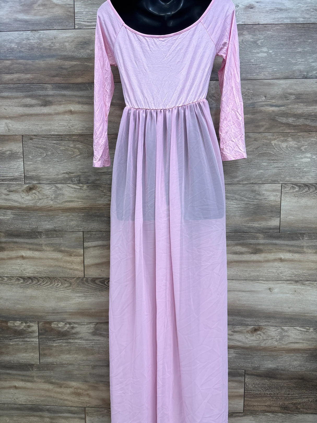 Front view of Odeerbi maternity pink off-shoulder maxi dress with long sleeves and sheer skirt overlay on wood background