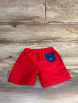 Back view flat lay of Andy & Evan toddler swim trunks in red showing elastic waistband and navy back pocket on wood background