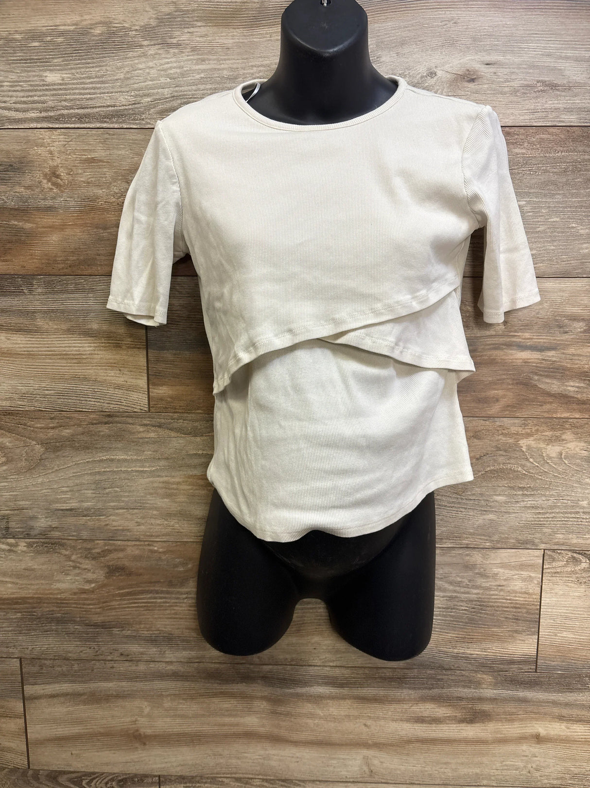 Front view of ivory H&M Mama ribbed nursing shirt, size L, layered overlap front and short sleeves on black mannequin with wood background