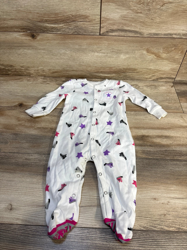 White baby onesie with Converse sneaker and star print, footed design, laid on wood floor