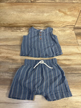 Flat lay of blue 2-piece baby henley tank top and shorts with wooden buttons and white drawstring on light wood background
