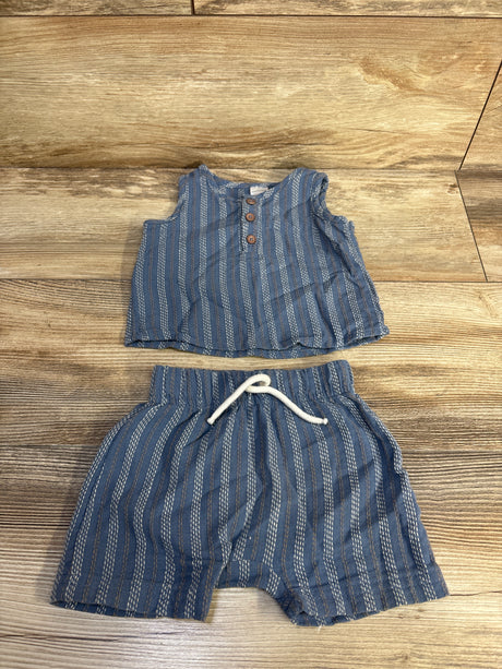 Flat lay of blue 2-piece baby henley tank top and shorts with wooden buttons and white drawstring on light wood background