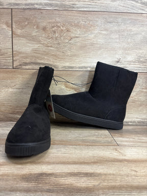 Pair of children's black suede ankle boots with flat rubber soles on wooden floor