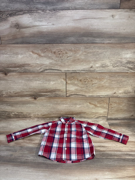 Front view of U.S. Polo Assn. toddler button-up shirt laid flat showing red plaid and chest pocket on wood background