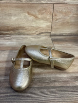 Angled view of Jumping Beans Susie T-strap ballet flats in metallic gold with textured upper and adjustable strap on wood