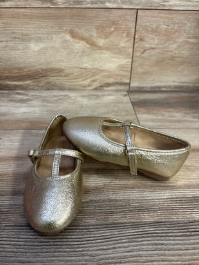 Angled view of Jumping Beans Susie T-strap ballet flats in metallic gold with textured upper and adjustable strap on wood
