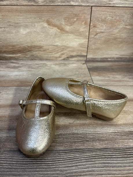 Angled view of Jumping Beans Susie T-strap ballet flats in metallic gold with textured upper and adjustable strap on wood