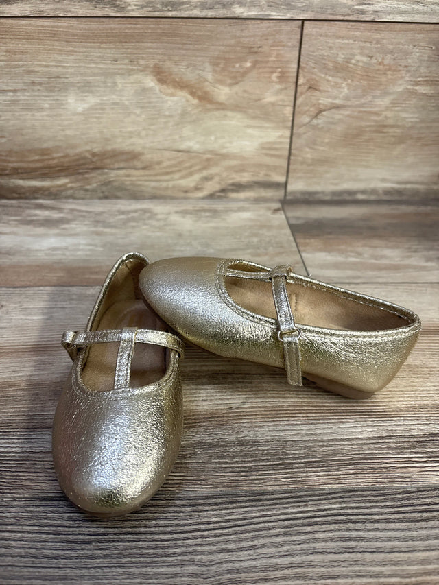 Angled view of Jumping Beans Susie T-strap ballet flats in metallic gold with textured upper and adjustable strap on wood