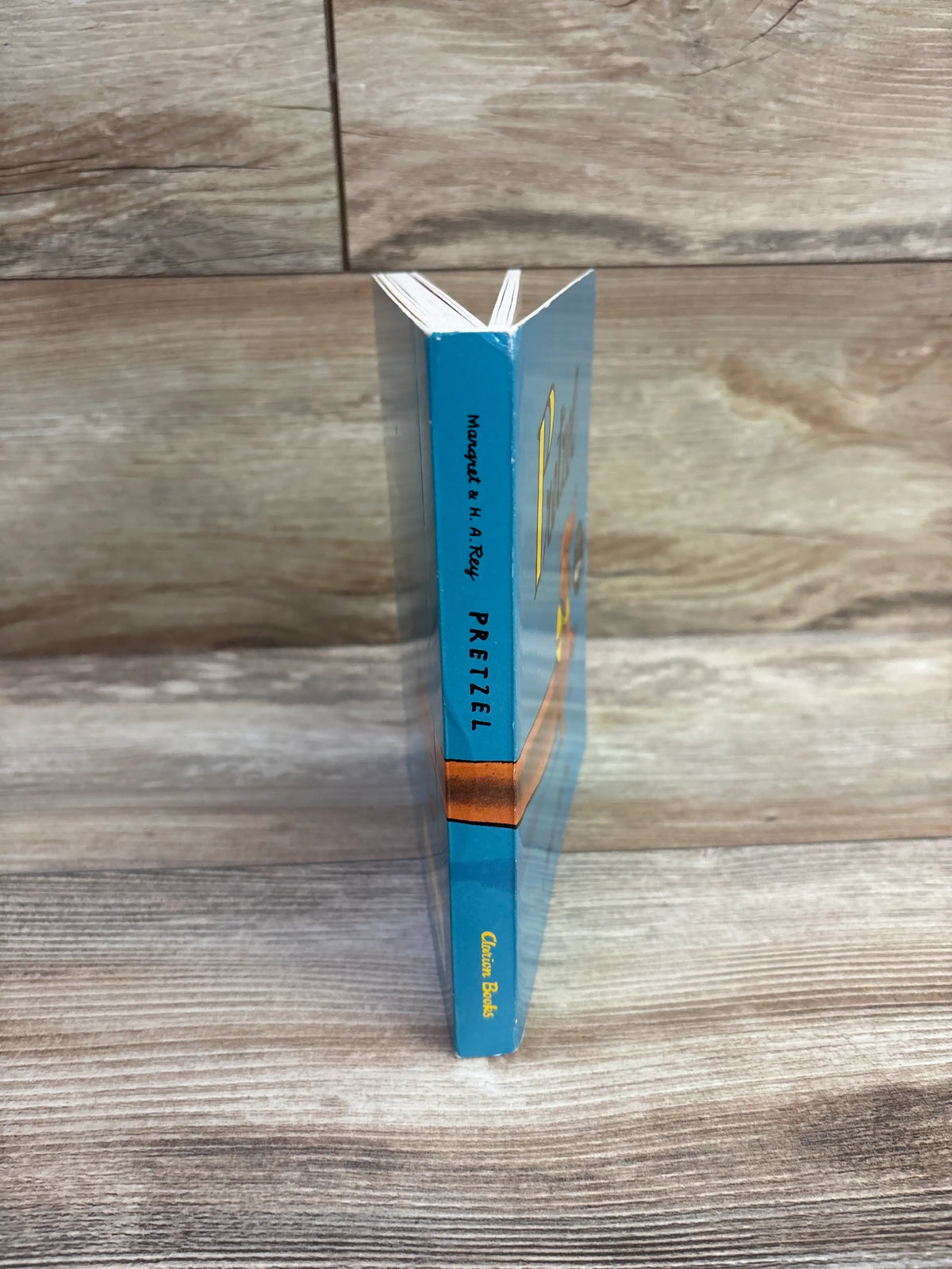 Side view of the blue Pretzel board book showing its spine and open board pages on a wood-grain surface