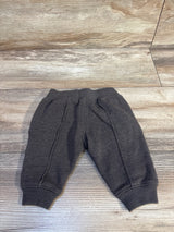 Gray baby joggers with elastic waist and cuffs, laid flat on wood floor