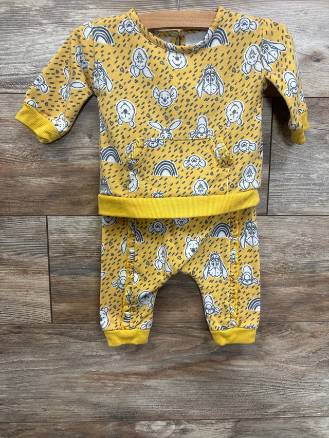 Yellow baby outfit set with cartoon character prints and rainbows on wooden background