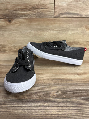 Pair of black canvas kids sneakers with white soles on wooden floor background, children's footwear