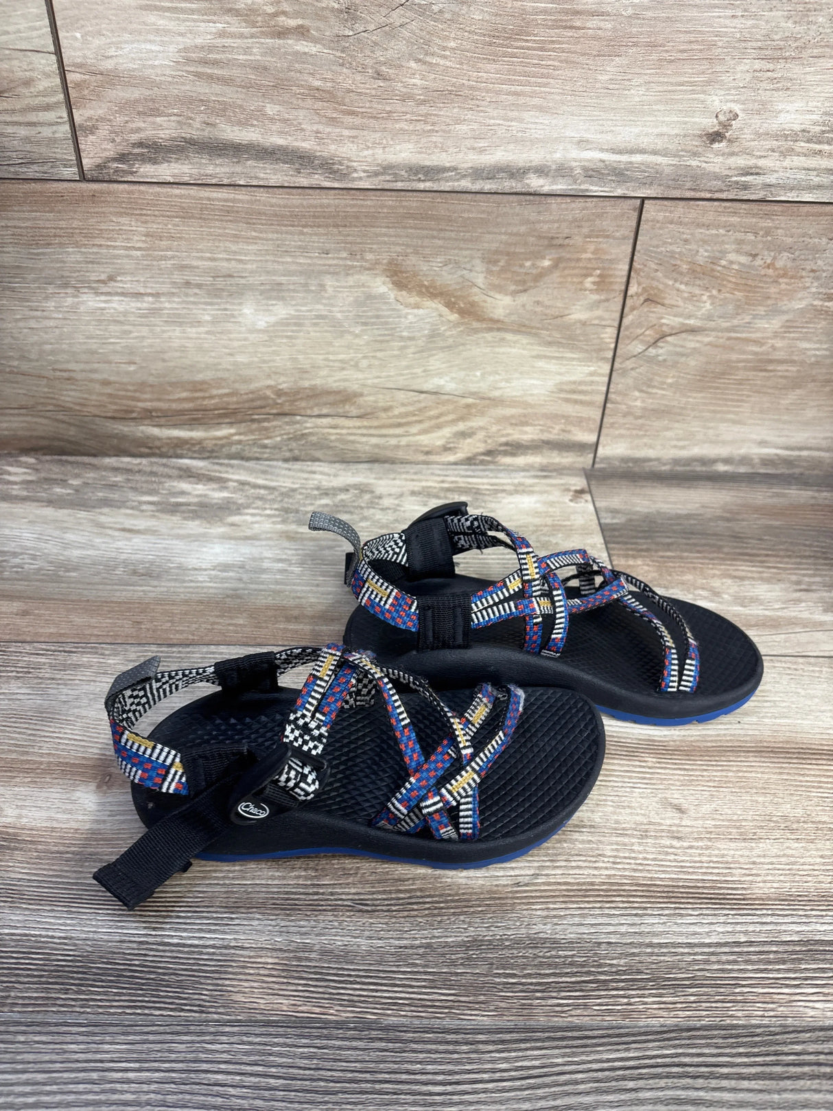 Angled view of Chaco ZX/1 Ecotread black sandals showing multicolor straps and textured footbed on wood floor