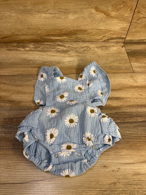Top-down view of blue gauze baby bubble romper with white daisy print, ruffle shoulder straps and snap crotch on wood floor