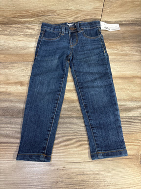 OshKosh blue denim jeans for kids displayed flat on wooden surface
