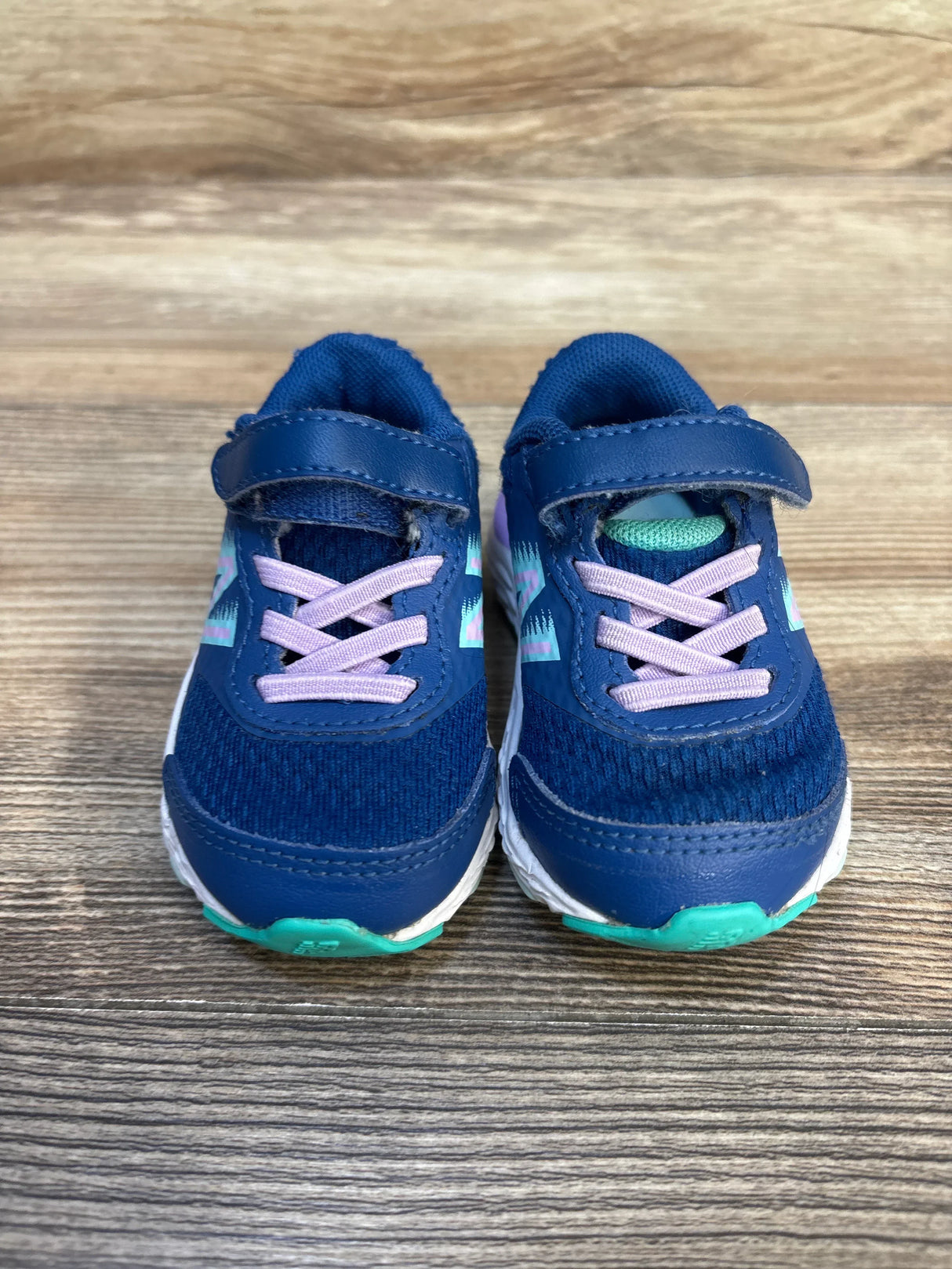 Blue toddler athletic shoes with velcro straps and pink laces on wood floor
