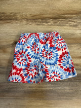 Front view of Jumping Beans 12M tie-dye swim trunks with red and blue spiral pattern and elastic waistband on wood floor