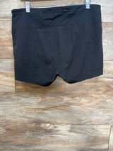 Front view of black GapFit maternity running shorts on hanger showing wide fold-over waistband with small zip pocket against wood plank background