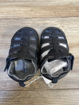 Top-down of Just One You Harrison fisherman sandals size 4/5c (12-18m) showing closed-toe navy straps and Velcro closures on wood
