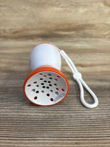 Front view of Baby Shusher Sleep Soother sound machine showcasing speaker grille, orange rim, and white wrist strap on wood surface