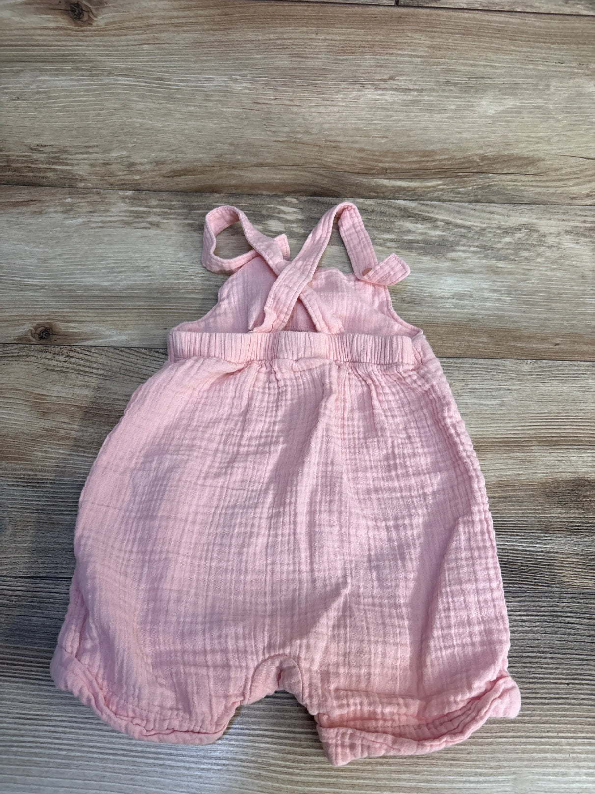 Top-down Baby Gap pink gauze shortalls 12–18M with crisscross straps, elastic waist, rolled leg hems on wood floor
