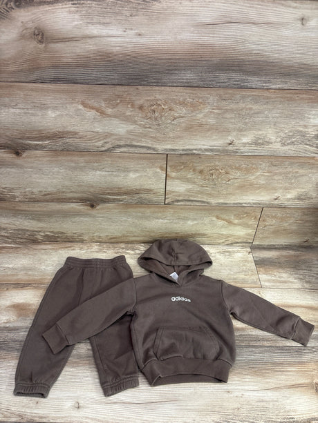 Overhead view of brown Adidas two-piece pullover sweatshirt and joggers set showcasing hood and elastic cuffs on wood planks