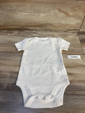 Top view of ivory Amazon Essentials bodysuit 3-6M with envelope neckline and three snap closures on wood background