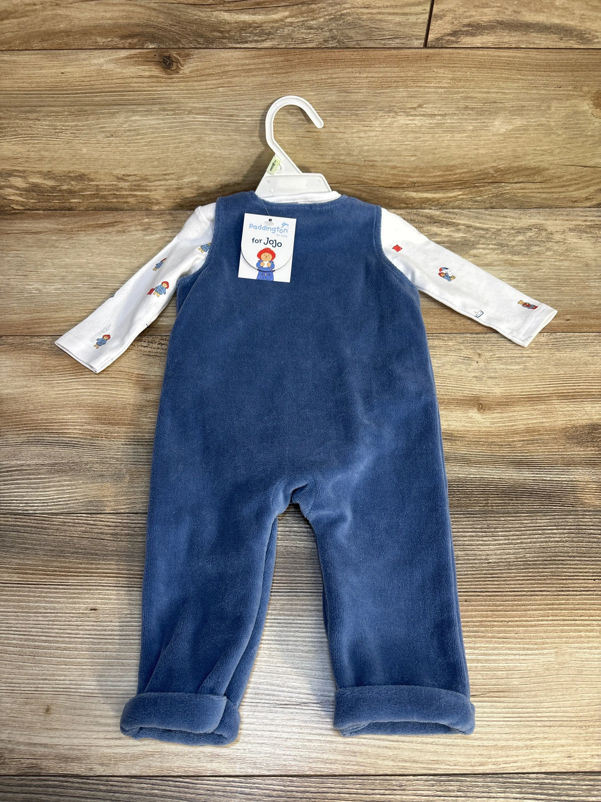 Back view of new Jojo Maman Navy Appliqué Dungaree Set in white and navy size 3-6m on hanger with hangtag on wood plank floor