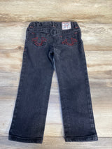 Black kids jeans with red stitching, back pockets, and logo patch on wood background
