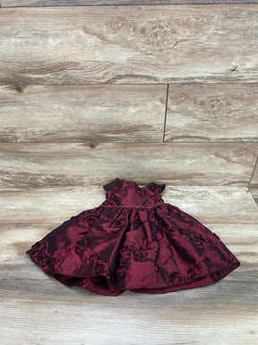 Front view of red cap-sleeve baby dress and matching bloomers with gathered waist and rosette texture on wood background