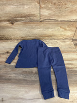 Flat lay of blue waffle-knit 2-piece baby pajama set, long-sleeve top and cuffed pants on wood background