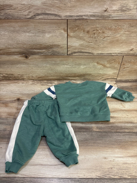Top view of Carter’s green 2pc sweatshirt and joggers set showcasing white stripes with a wood background