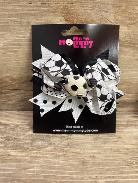 Front view of soccer ball applique layered hair bow with black-and-white soccer-print ribbons on a display card