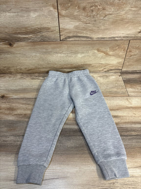 Gray Nike toddler sweatpants with purple logo, laid flat on wood floor for kids clothing resale