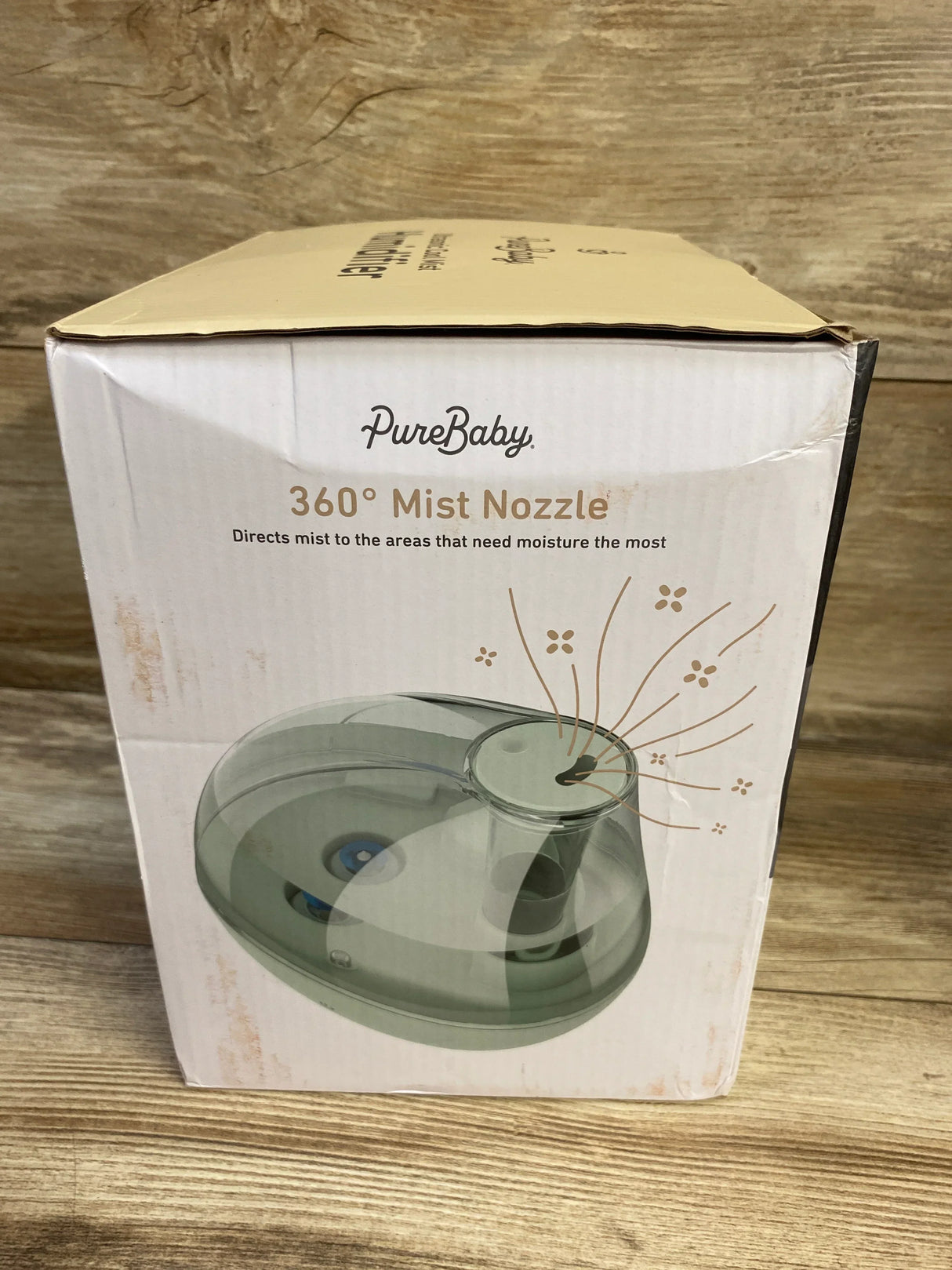 Front view of PureBaby Ultrasonic Cool Mist Humidifier box showcasing 360 degree Mist Nozzle graphic on wooden surface