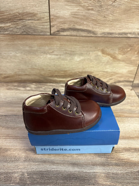Side view of brown Stride Rite SRTech Elliot toddler sneakers showing leather upper, laces, and padded collar on blue Stride Rite box
