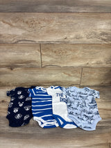 Front view of 4 pack light blue 6 month baby bodysuits showing dog print, striped, and text designs on wood background