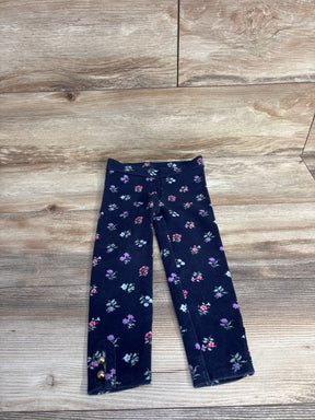 Navy blue floral leggings with small colorful flowers and gold button accents on wooden surface