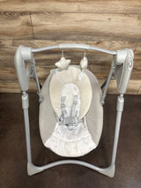 Top view of Graco Slim Spaces compact swing with beige seat, rainbow-print insert, five-point harness and toy bar