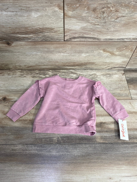 Light pink long-sleeve baby sweatshirt with tag laid on wood textured floor, kids clothing
